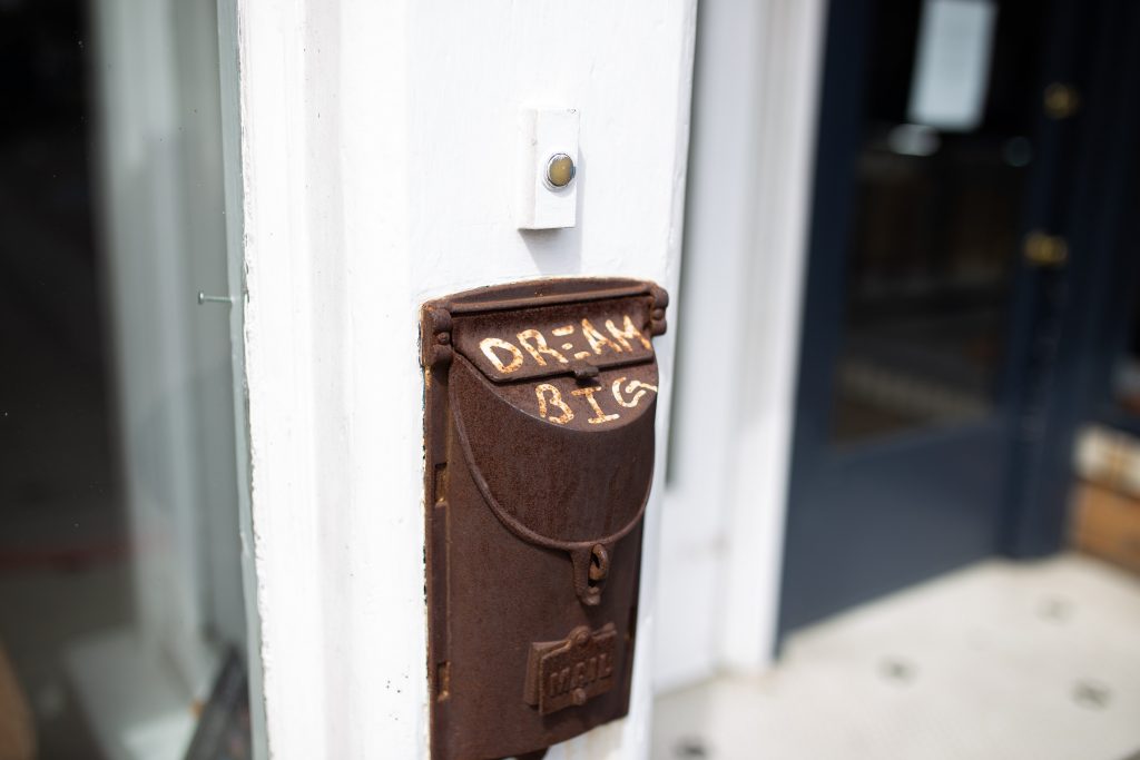 Rusted wall-mounted mailbox with 'dream big' written on it.